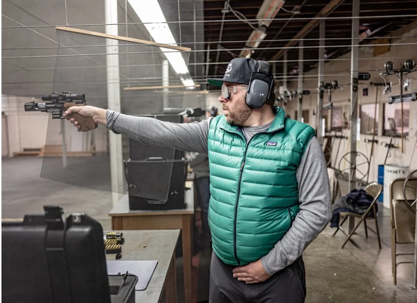 A shooter on the PRPC indoor range in a green vest, taking aim