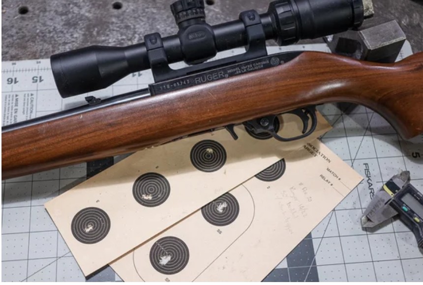 A scoped smallbore rifle resting beside scored competition targets